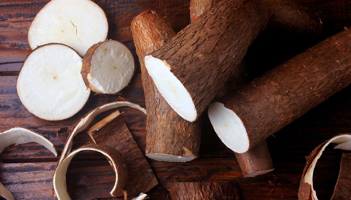fresh cassava and peels and slices on rustic wooden table. Top view